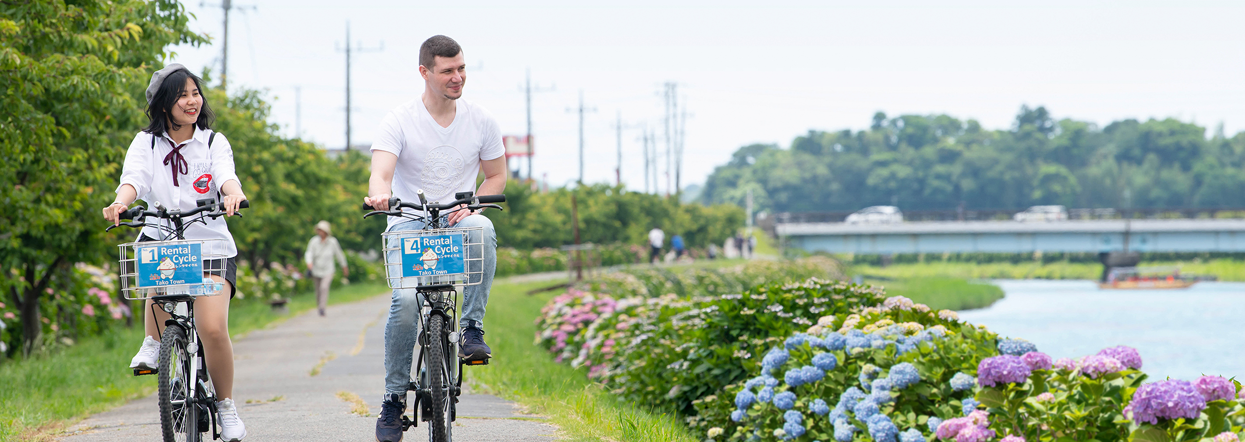 Visitors cycling along a riverside path in Tako Town